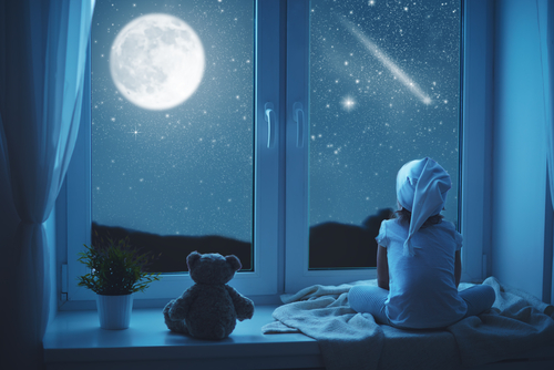 criança pensando na vida sentada na cama antes de formir